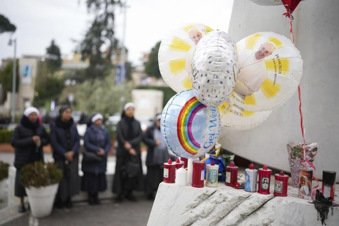 Świeczki, kartki z życzeniami, balony w kształcie serca, kwiaty składane są pod pomnikiem Jana Pawła II przed rzymską Polikliniką Gemelli