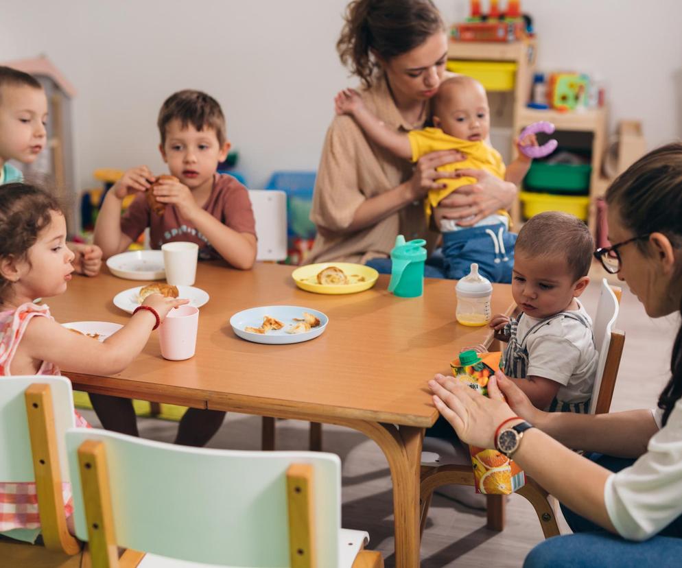 Dzieci w żłobku przy stoliku razem z nauczycielkami