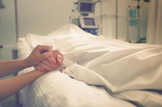 Bliska osoba trzyma chorego leżącego w szpitalu
