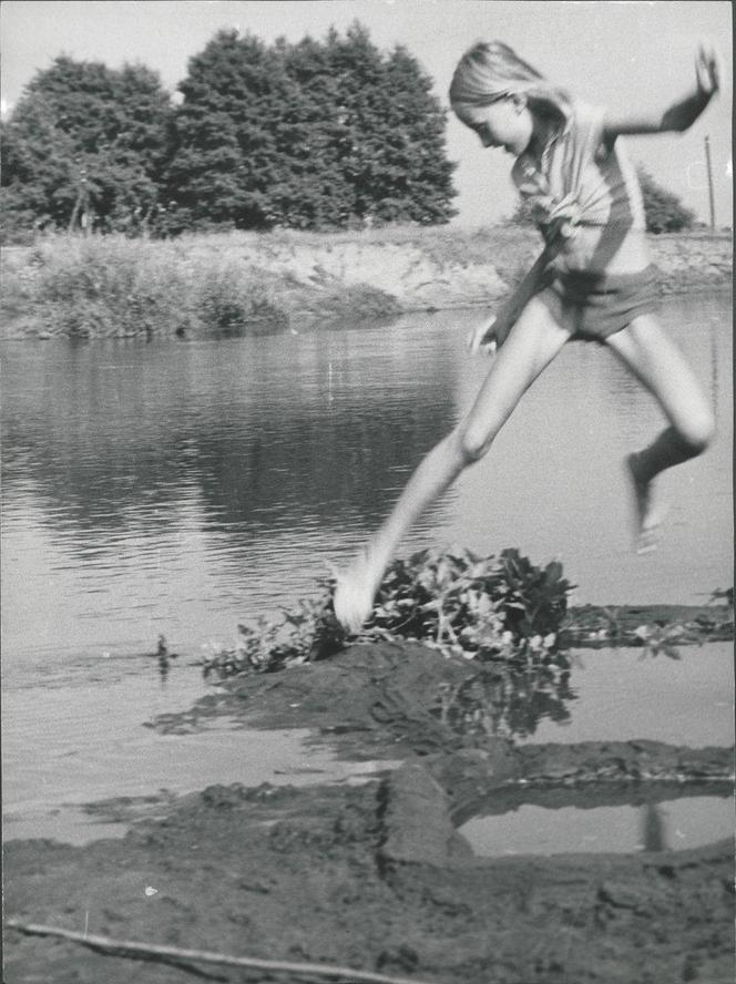 Skacząca dziewczynka nad rzeką Prosną w Piwonicach koło Kalisza. Fotografia z 1971 r. APK, Spuścizna Stanisława Perlińskiego z Kalisza