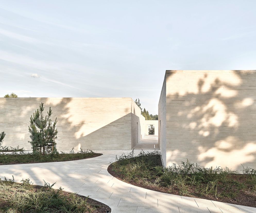 Kolumbarium w Radomiu – nowoczesna architektura cmentarna z piaskowca szydłowieckiego, gdzie proste bloki tworzą korytarze i place kontemplacji. Naturalne materiały podkreślają powagę miejsca. Więcej o tej realizacji na Architektura Murator Plus.