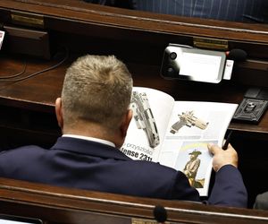 W  czasie obrad Sejmu poseł przeglądał katalog z bronią