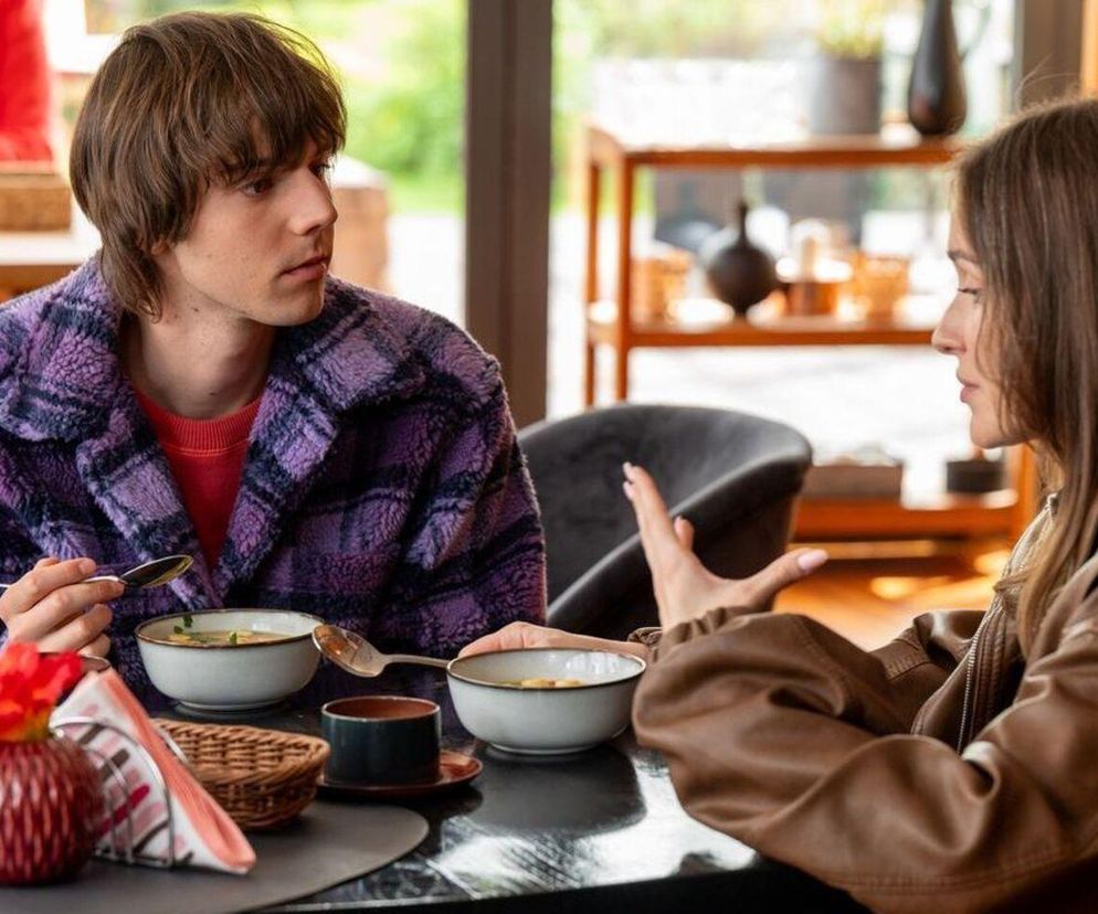 Madzia (Natalia Sierzputowska) i Wiktor (Grzegorz Kestranek) siedzą w Feel Good, rozmawiając przy stole. Madzia, w brązowej kurtce, gestykuluje, podczas gdy Wiktor, w fioletowym płaszczu w kratę, patrzy na nią, trzymając łyżkę nad miską z zupą. Kontekst odcinka Barwy Szczęścia o sporze w fundacji dostępny jest na Super Seriale.