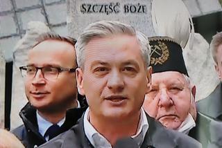 Robert Biedroń na tle religijnego hasła