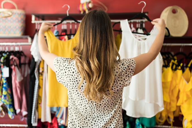 kobieta stojąca tyłem i wybierająca ubrania w sklepie