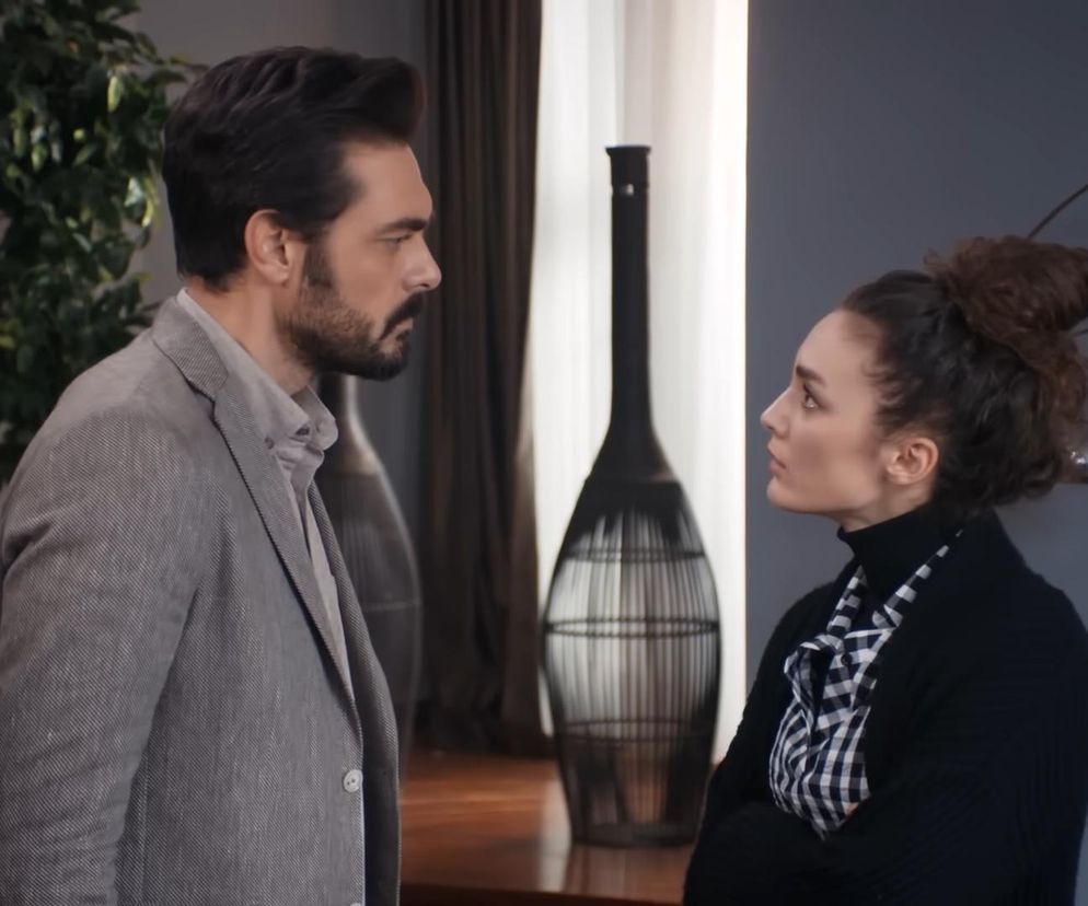 Yaman w szarym garniturze i Nana w czarnym golfie oraz koszuli w kratę, intensywnie patrzą sobie w oczy w 705. odcinku Dziedzictwa, dyskutując w pomieszczeniu z rośliną i ozdobnymi lampami. Więcej o ich relacji przeczytasz na Super Seriale.