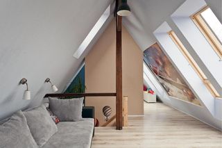 Przed ścianą kominową jest wejście na poddasze ze schodami. Nad nimi zaprojektowano okno dachowe – mniejsze niż te w skosie po przeciwnej stronie. Za kominem urządzono miejsce do spania oraz zabawy