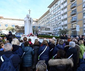 Wierni modlą się o zdrowie Franciszka przed pomnikiem Jana Pawła II. Składają kartki z życzeniami i wiązanki z białych róż