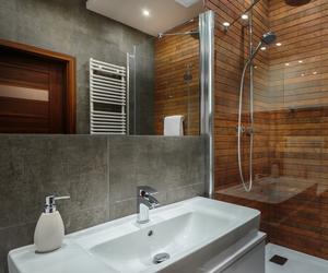 Łazienka w szarości i drewnie - akcent w strefie prysznica 