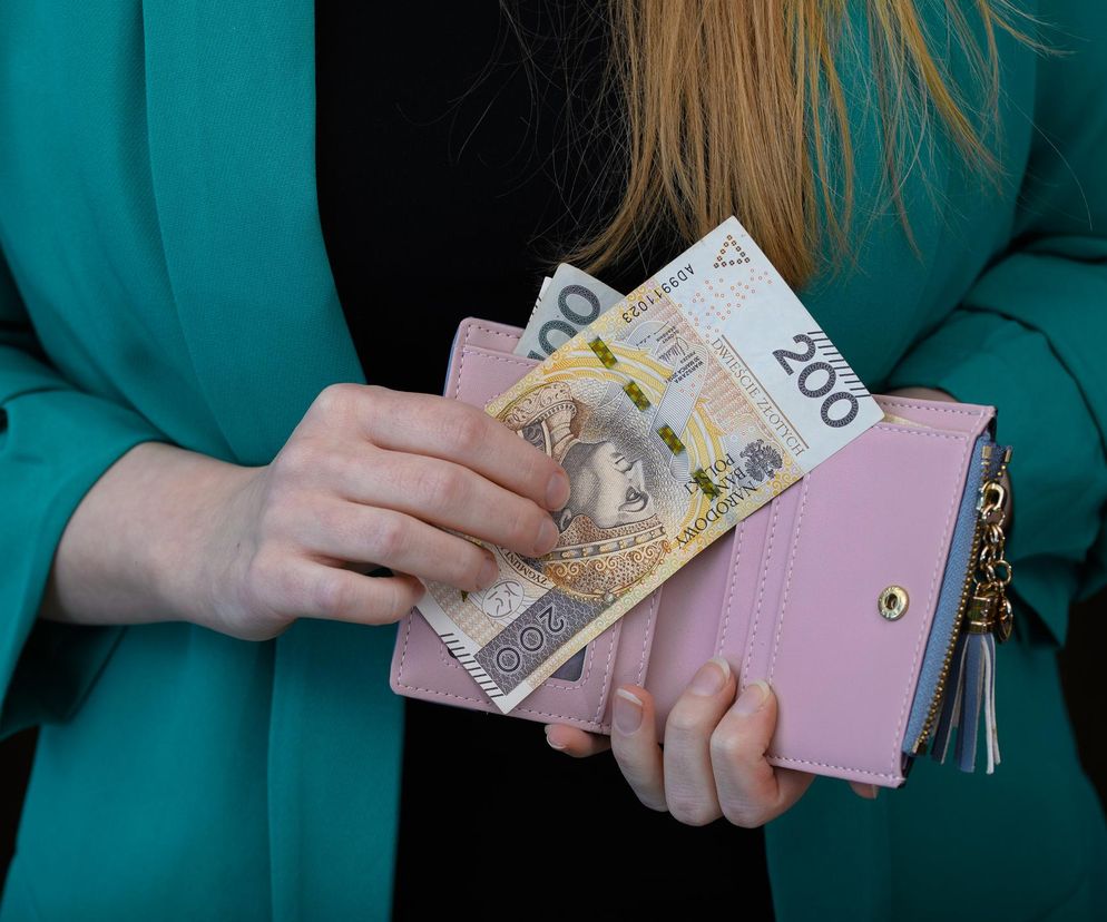Kobieta wyjmująca banknot 200 zł z portfela symbolizuje nowy dodatek mieszkaniowy 2025 dla służb mundurowych. Świadczenie w wysokości od 900 do 1800 zł miesięcznie ma wspierać koszty utrzymania i wynajmu mieszkań. Więcej informacji znajdziesz na Poradnik Zdrowie.