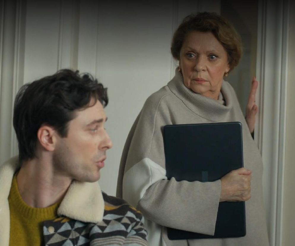 Józefina (Elżbieta Jarosik) z zatroskaną miną, trzymając laptop, patrzy na Cezarego (Marcel Opaliński), który rozmawia. Scena z serialu Barwy szczęścia odcinek 3242, dostępna do przeczytania na Super Seriale.