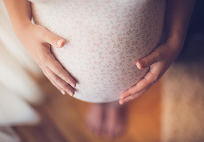 Zbliżenie na brzuch kobiety w ciąży. Czy szczepienia przeciw COVID-19 w ciąży są bezpieczne?