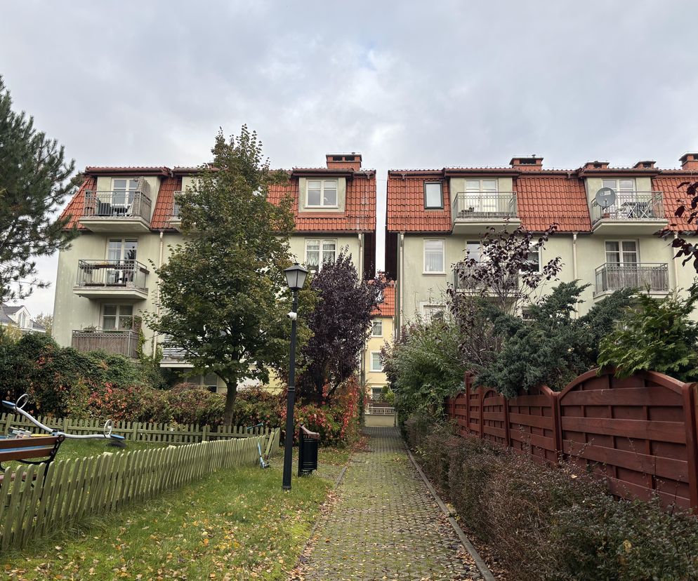 Osiedle Polana Świemirowska w Sopocie, budynki z jasnymi elewacjami, balkonami i czerwoną dachówką. Widoczny wąski chodnik, zieleń, ogrodzenie. O znaczeniu tego projektu dla polskiej architektury przeczytasz na Architektura Murator Plus.