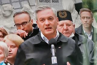 Robert Biedroń na tle religijnego hasła