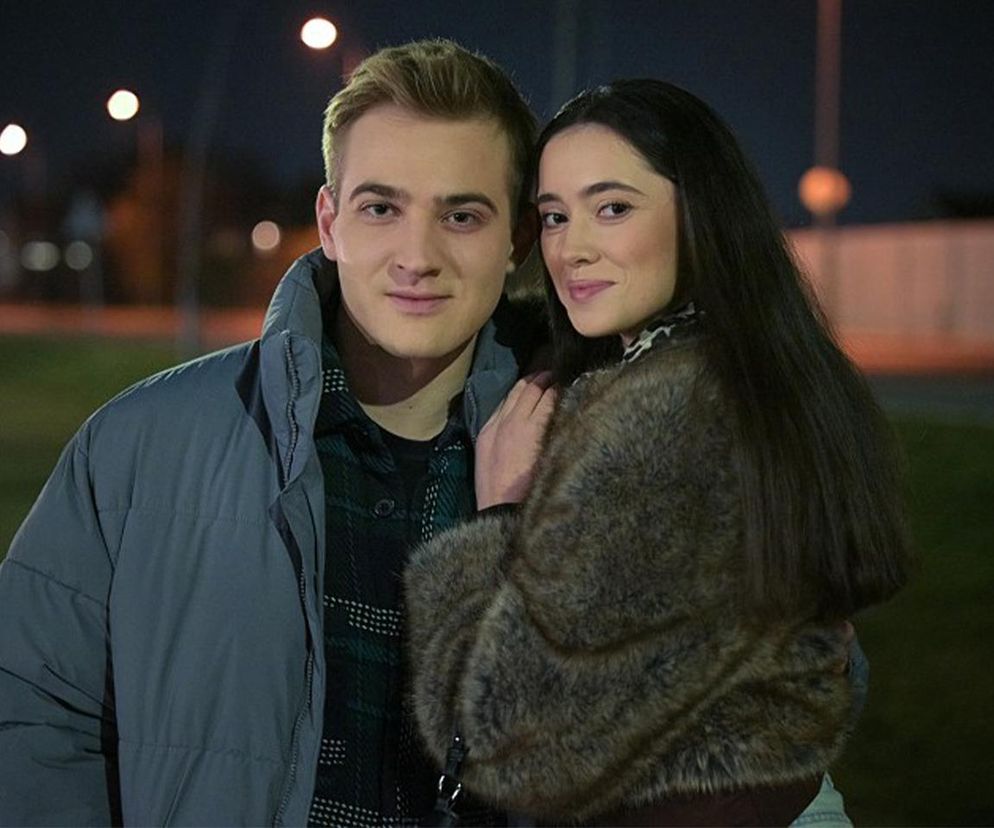Igor Paszczyk jako Biały i Patrycja Franczak jako Angelika, uśmiechnięci, pozują na tle nocnego krajobrazu z rozmazanymi światłami ulicznymi. Angelika w futrzanej kurtce z długimi włosami, Biały w puchowej kurtce i koszuli w kratę. Więcej o ich losach na Super Seriale.