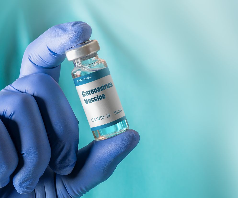 Dłoń w niebieskiej rękawiczce trzyma fiolkę ze szczepionką przeciw COVID-19. Na etykiecie napis Coronavirus Vaccine i SARS-CoV-2. Informacje o dodatkowych dawkach i ich skuteczności znajdziesz na Poradnik Zdrowie.