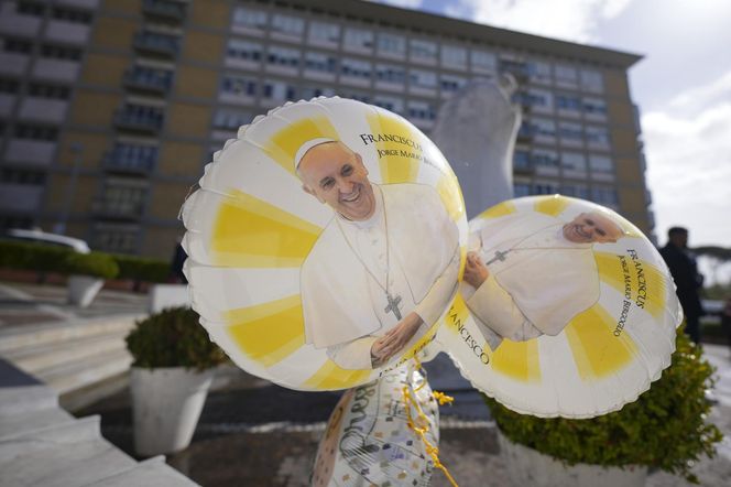 Świeczki, kartki z życzeniami, balony w kształcie serca, kwiaty składane są pod pomnikiem Jana Pawła II przed rzymską Polikliniką Gemelli