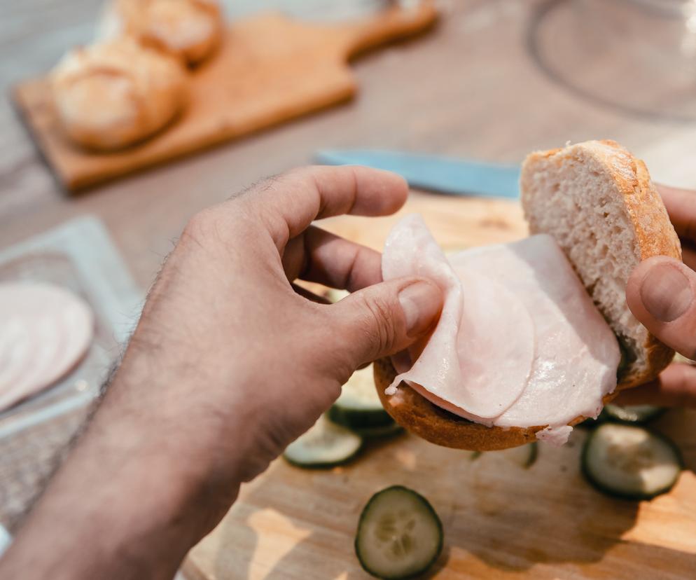 Mężczyzna robi kanapkę z wędliną