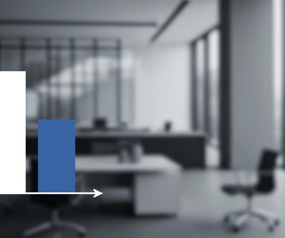 W centrum obrazu widoczny jest dwuwymiarowy wykres słupkowy. Składa się z białej osi pionowej zakończonej strzałką skierowaną w górę oraz białej osi poziomej zakończonej strzałką skierowaną w prawo. Na osi poziomej znajdują się dwa słupki: pierwszy, po lewej, jest koloru białego i jest wyższy, natomiast drugi, po prawej, jest koloru niebieskiego i jest niższy. Tło obrazu jest rozmyte i przedstawia wnętrze nowoczesnego biura w odcieniach szarości i bieli, z biurkami i krzesłami obrotowymi oraz dużymi oknami.