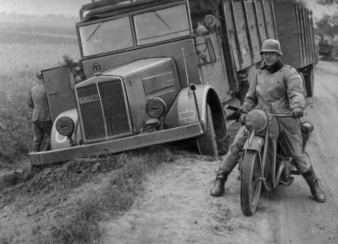 Wypadek samochodu ciężarowego marki Krupp. Obok leżącej w rowie ciężarówki widoczny motocyklista niemiecki na motorze BMW R-12