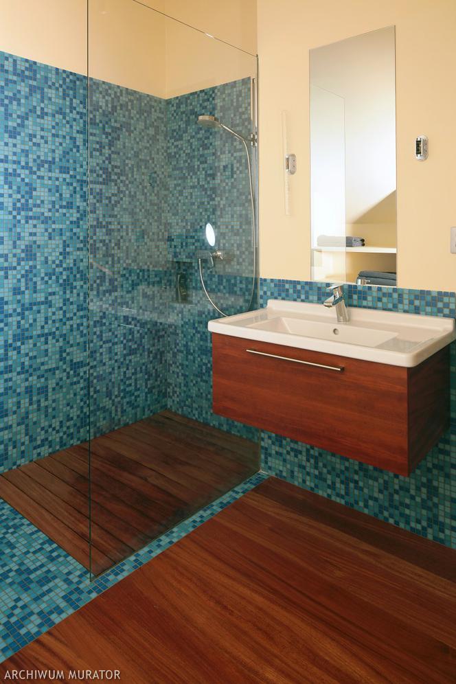 Drobna mozaika i ciepły odcień drewna  w niebieskiej łazience
