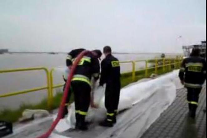 Powódź w Tczewie. Strażacy układają rękaw przeciwopowodziowy 