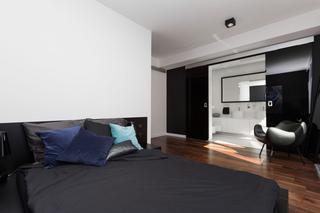 Nowoczesna sypialnia z łazienką: czarna ściana i ikony designu w minimalistycznym wnętrzu