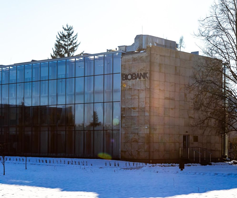 Budynek Biobanku Świętokrzyskiego w Chęcinach, z nowoczesną szklaną fasadą i kamiennymi panelami, widoczny w zimowej scenerii. Obiekt, dawniej szkoła tysiąclatka, to przykład adaptacji architektonicznej, o której przeczytasz na Architektura Murator Plus.