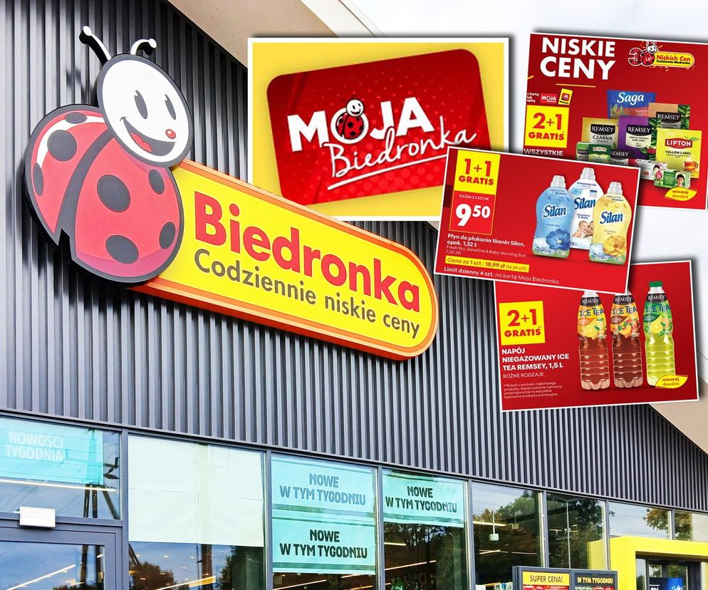 Budynek sklepu Biedronka z widocznym logotypem. Na zdjęciu dodatkowo grafiki z promocjami 1+1 i 2+1 gratis na produkty, takie jak płyny do płukania tkanin Silan, herbaty Lipton oraz napoje Ice Tea Remsey. O wszystkich tych promocjach przeczytasz na Super Biznes.
