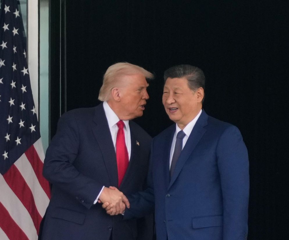 Donald Trump i Xi Jinping uściskiem dłoni ogłaszają rozejm handlowy między USA a Chinami na tle amerykańskiej flagi. Ich porozumienie to kluczowy temat, o którym możesz przeczytać więcej na Super Biznes.