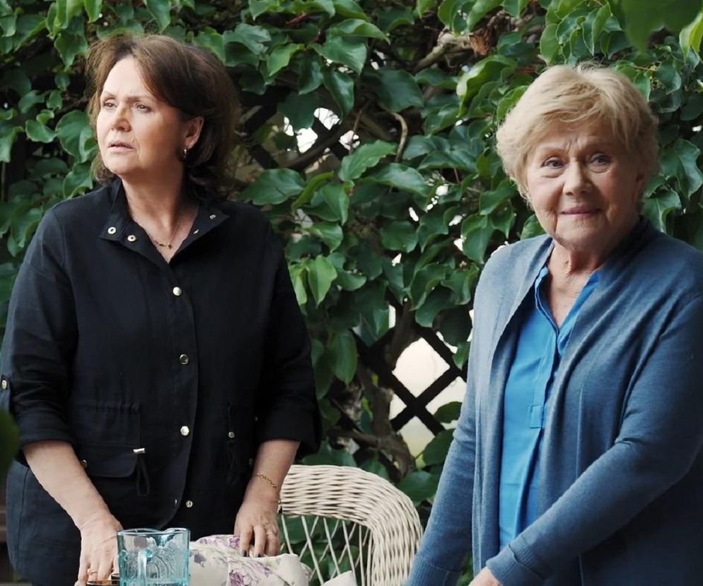 Aktorzy serialu M jak miłość. Kobieta po lewej w ciemnej koszuli z guziczkami, kobieta po prawej w jasnoniebieskiej bluzce i szarym sweterku. W tle zielone pnącza. W artykule na Super Seriale przeczytasz o zmianach w ramówce M jak miłość.