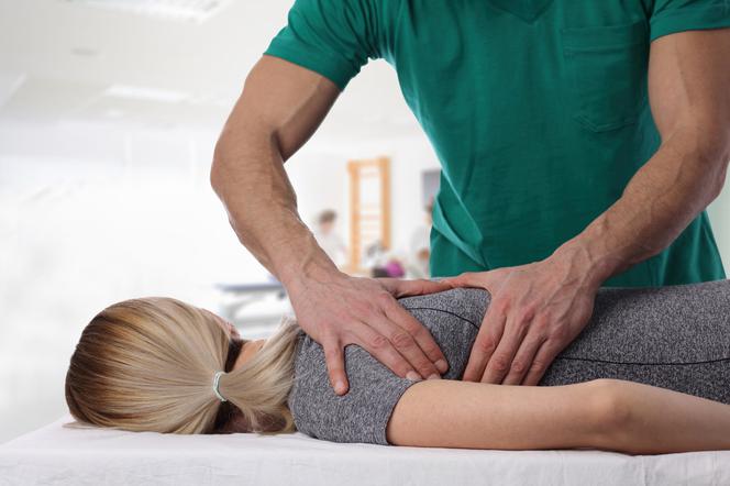 Osteopata wykonujący masaż pleców pacjentce. 