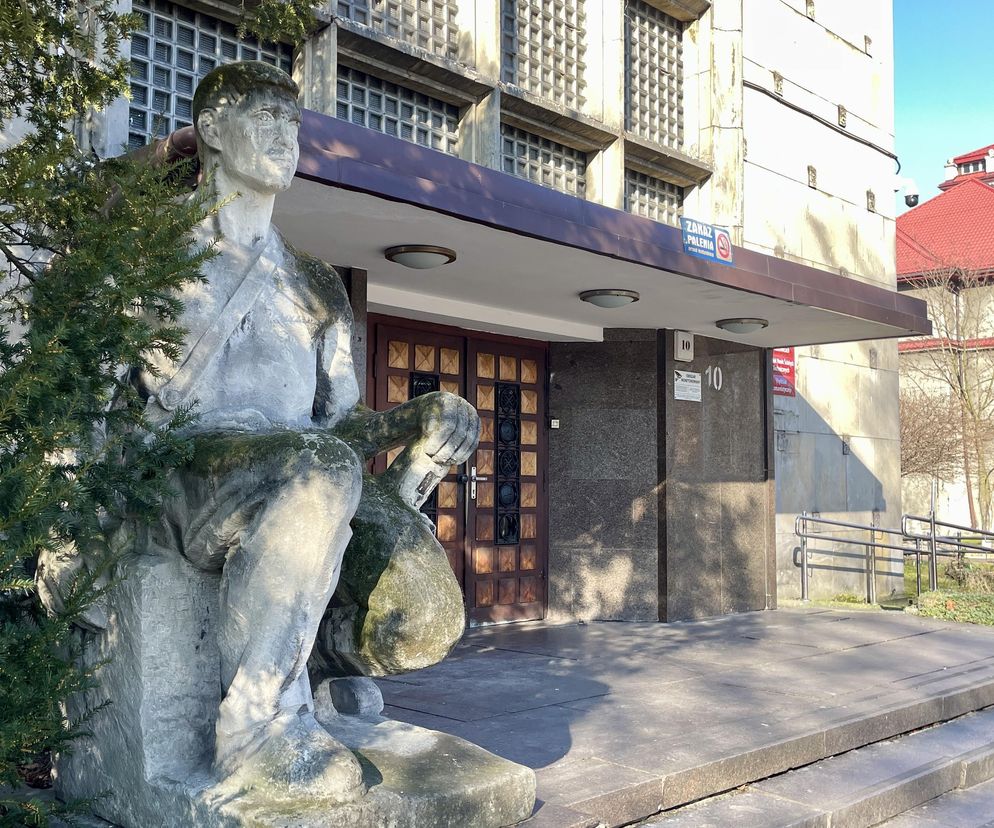 Monumentalne rzeźby ludzi pracy przed wejściem do Domu Kultury Górnik w Sosnowcu, charakterystyczne dla architektury socrealistycznej. Budynek z elewacją z luksferów i czerwonobrązowym daszkiem, o którym przeczytasz więcej na Architektura Murator Plus.