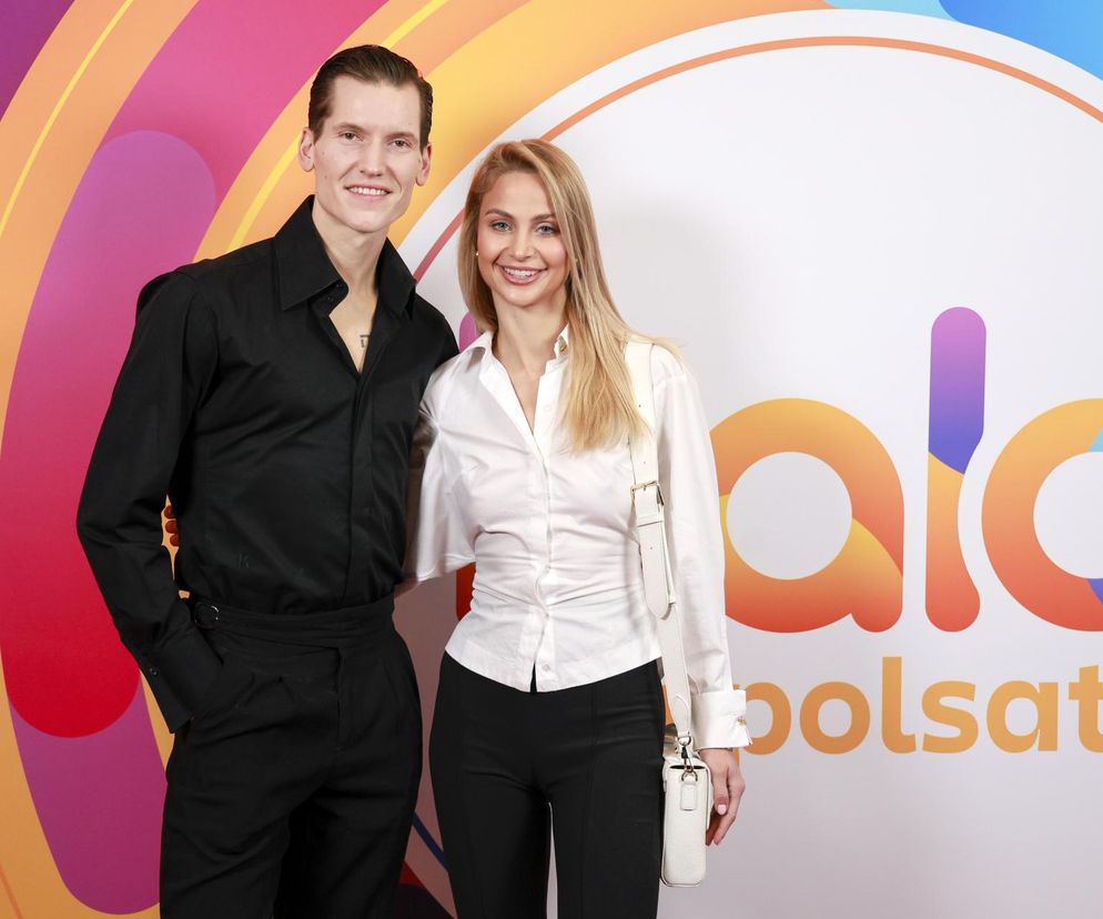 Hanna Żudziewicz i Jacek Jeschke pozują razem, Jacek w czarnej koszuli, Hanna w białej, na tle z logo Polsatu. Para uśmiecha się do obiektywu, a o ich dramatycznych przeżyciach przed ślubem przeczytasz więcej na naszym portalu.