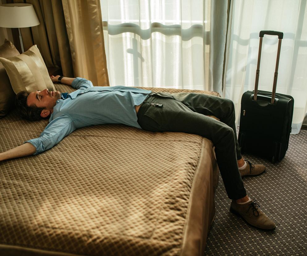 Mężczyzna leży na łóżku w hotelu