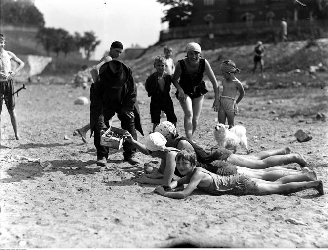 Plażowicze podczas wypoczynku. Widoczny sprzedawca obwarzanków. Zdjęcie zrobione w 1929 roku 