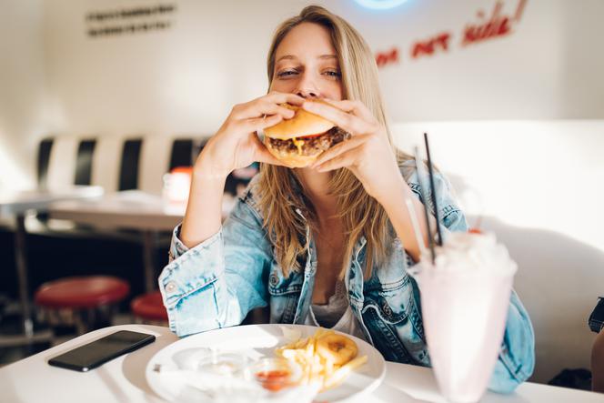 młoda kobieta jedząca burgera