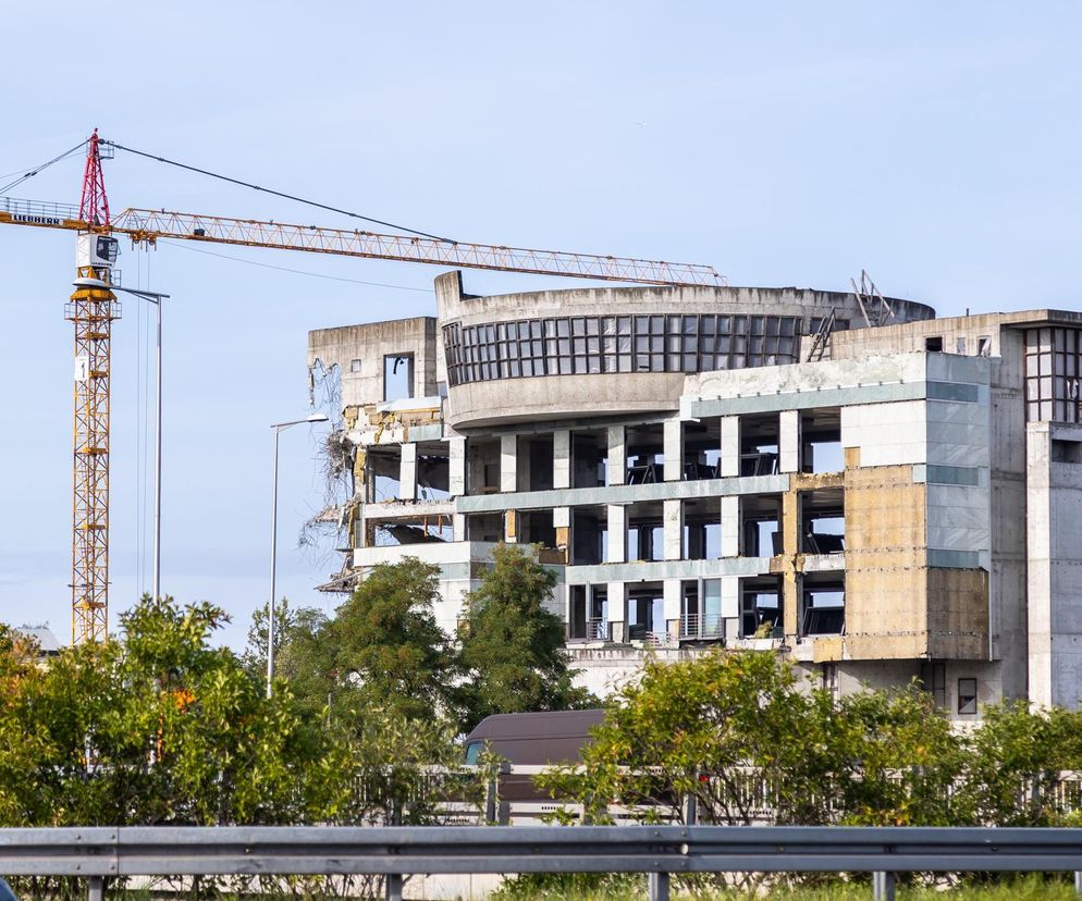 Budynek w trakcie rozbiórki lub budowy z dźwigiem Liebherr na tle jasnego nieba. Obiekt na warszawskim osiedlu Literacka symbolizuje zamrożenie inwestycji i problemy z planowaniem przestrzennym, o których przeczytasz na Super Biznes.