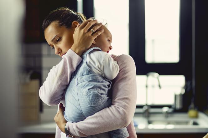 Zaniepokojona matka tuli w ramionach niemowlę