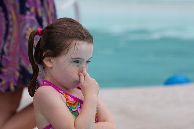 Dziewczynka zatykająca nos na basenie przed skokiem do wody