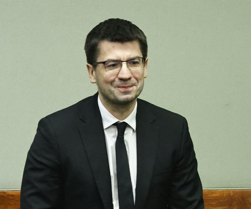 Mariusz Haładyj, prezes Najwyższej Izby Kontroli, w ujęciu od pasa w górę, ubrany w elegancki garnitur z krawatem, uśmiecha się podczas wywiadu. Zdjęcie ilustruje ważną dyskusję o deregulacji i biurokracji w Polsce, o czym można przeczytać na portalu Super Biznes.