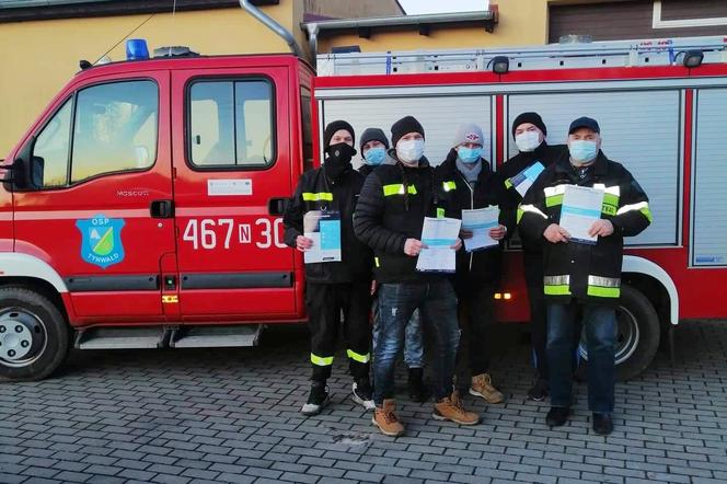 Strażacy z OSP dostarczają ulotki na temat szczepień do mieszkańców powiatu iławskiego