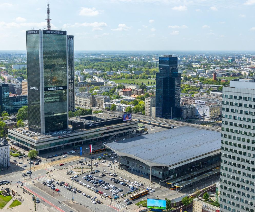 Panorana centralnej Warszawy z widokiem na wieżowce: Presidential, budynek z logo Samsunga, oraz Dworzec Centralny, otoczone zielenią i miejską infrastrukturą. Inwestycje w Warszawie, jak te opisane na Architektura Murator Plus, zmieniają jej oblicze.