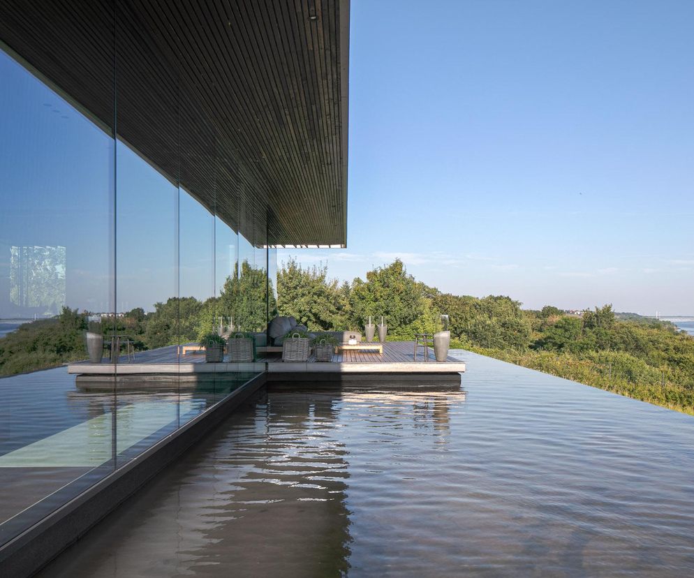 Nowoczesny dom na skarpie autorstwa arch. Pawła Naduka z przeszkloną ścianą i basenem typu infinity, wtapiający się w zielony krajobraz rzeki Wisły. Projekt, o którym przeczytasz na portalu Architektura Murator Plus, prezentuje harmonię z otoczeniem, oferując widok na rzekę i Płock.