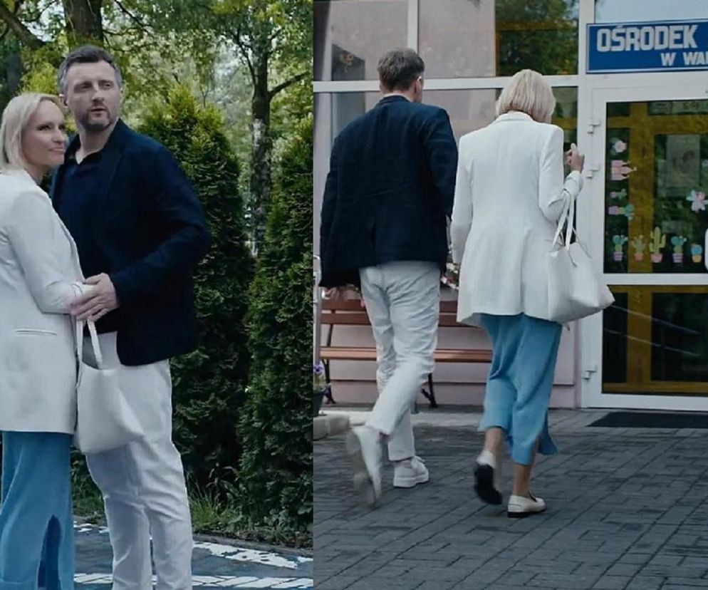 Dorota i Bartek z serialu M jak miłość wchodzą do Ośrodka Adopcyjnego w Warszawie. Para trzyma się za ręce, odczuwając radość, ekscytację i strach. Obok napisu Ośrodek Adopcyjny widoczne są kolorowe ozdoby na szybie. Więcej o ich losach przeczytasz na Super Seriale.