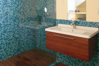 Drobna mozaika i ciepły odcień drewna  w niebieskiej łazience