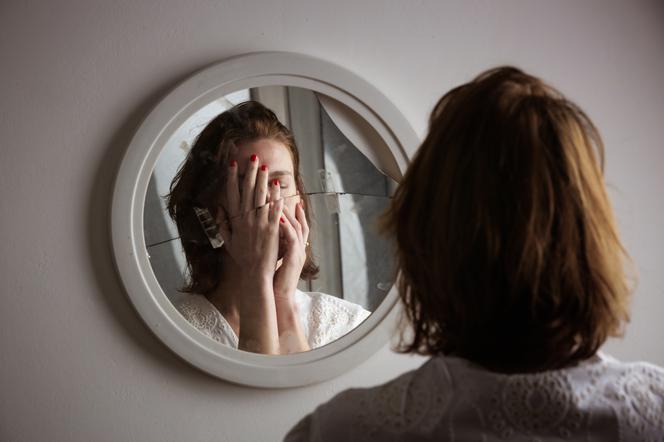 Zestresowana kobieta przed potłuczonym lustrem