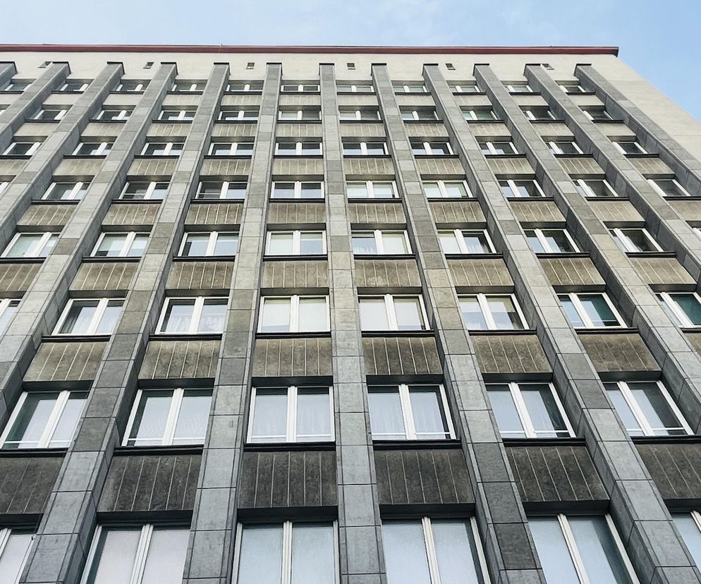 Fasada Drapacza Chmur w Chorzowie, z funkcjonalistyczną architekturą i rzędem okien, widziana od dołu. Budynek z 1937 roku, projekt Stanisława Tabeńskiego, charakteryzuje się elewacją z tynku z miką. Więcej o nim na portalu Architektura Murator Plus.