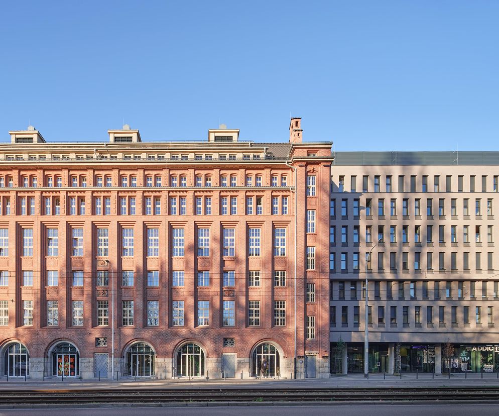 Dom studencki BaseCamp we Wrocławiu to imponujący ceglany budynek dawnej piekarni „Mamut” z zaadaptowanymi i nowoprojektowanymi skrzydłami. Na zdjęciu widać budynek z cegły i nowy, jasno szary, z dużymi oknami. O jego architekturze dowiesz się na Architektura Murator Plus.