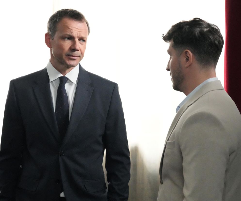 Bruno (Lesław Żurek) w ciemnym garniturze i Justin (Jasper Sołtysiewicz) w jasnej marynarce rozmawiają, stojąc naprzeciwko siebie, co wskazuje na kolejny konflikt w serialu Barwy szczęścia. Zdjęcie ilustruje scenę, o której można przeczytać na portalu Super Seriale.